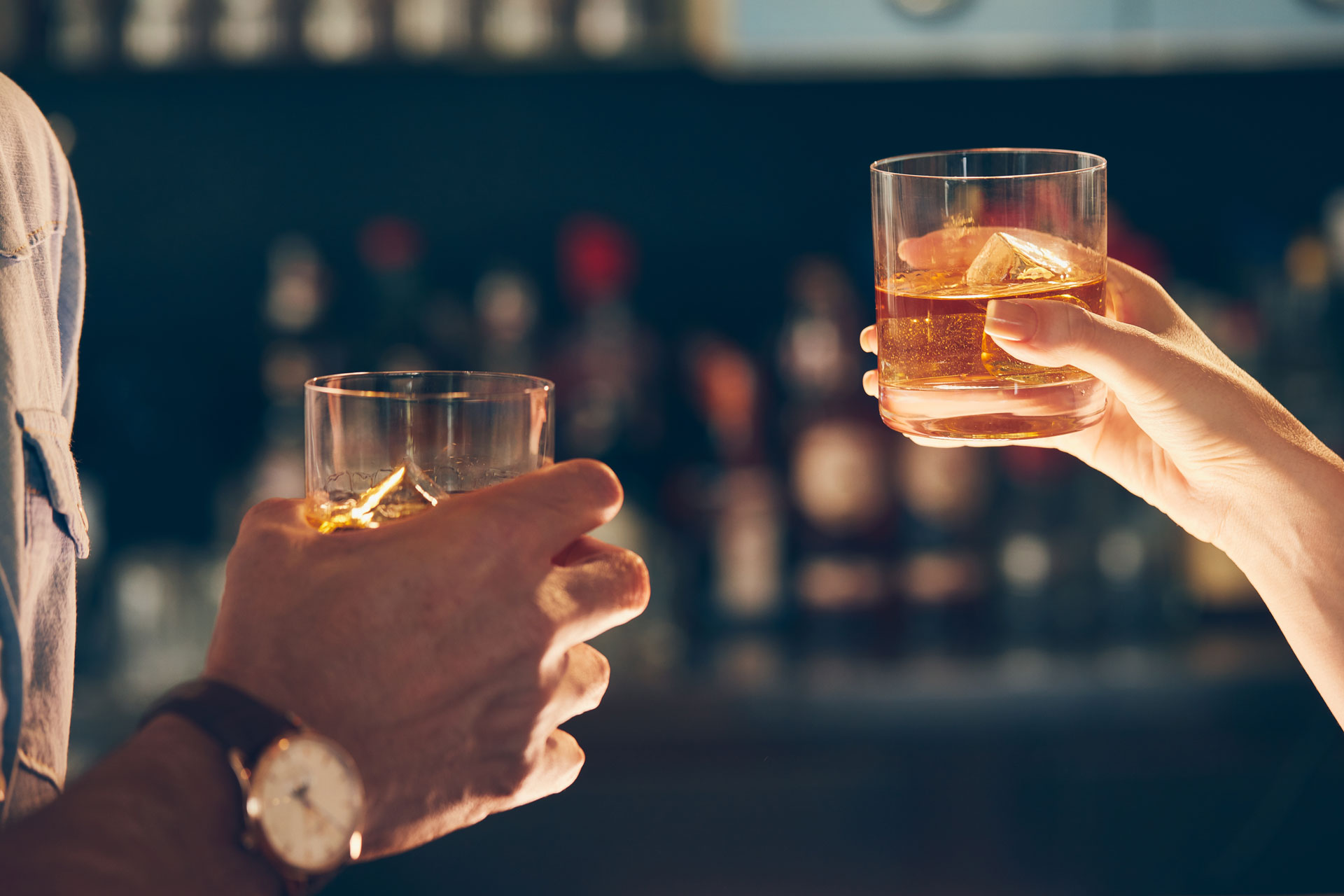 closeup shot of two people clinking glasses with a